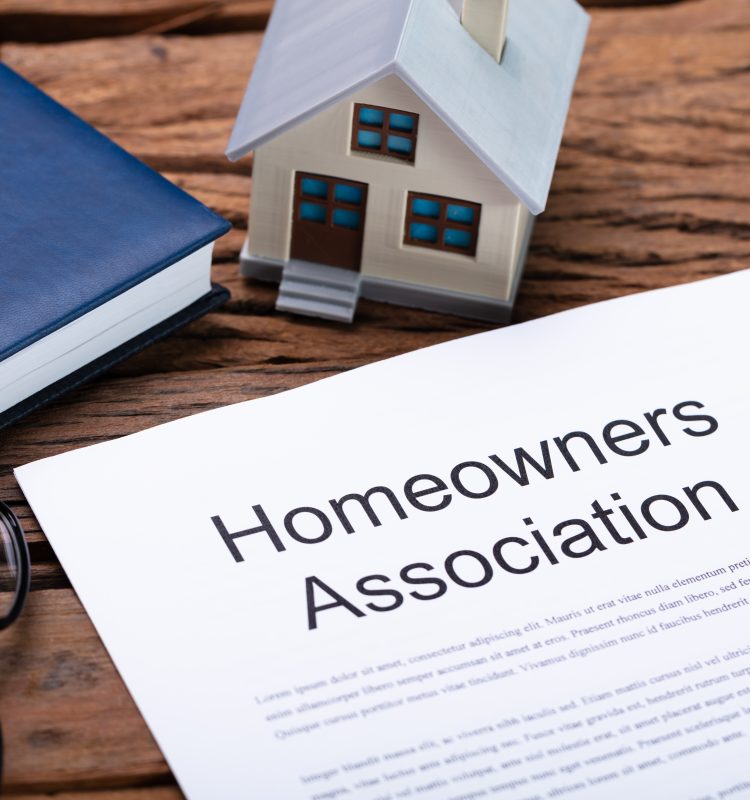 a contract with homeowners association listed on it with a book and a house framing the document.